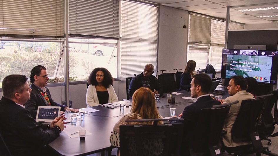 Oito pessoas sentadas em torno de uma mesa de reunião.